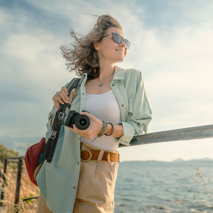 woman smiling while leaning on railing near waterfront