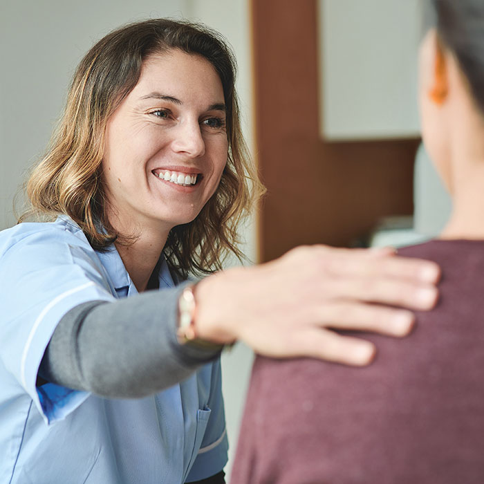 woman working in clinic and smiling with hand rested on patient