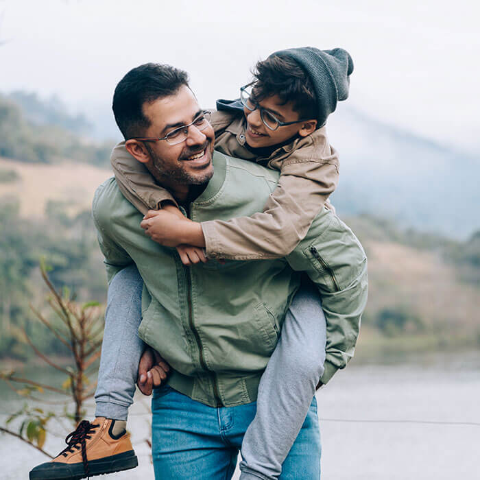 father giving son a piggyback ride outside