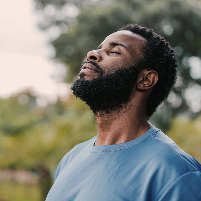 man outdoors with eyes closed and head tilted upward