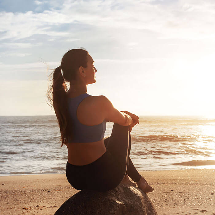 woman sitting on the beach at sunset