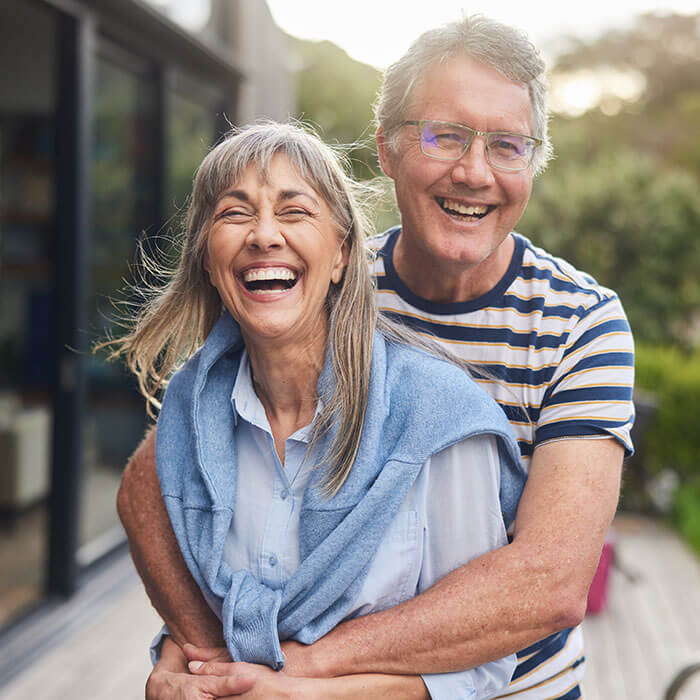 mature man and woman smiling together outside home