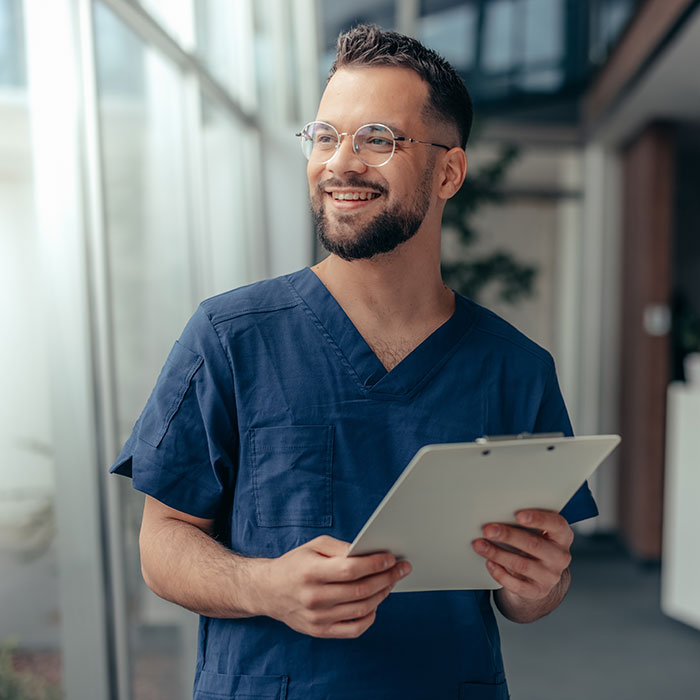 man working in clinic and smiling while holding clipboard