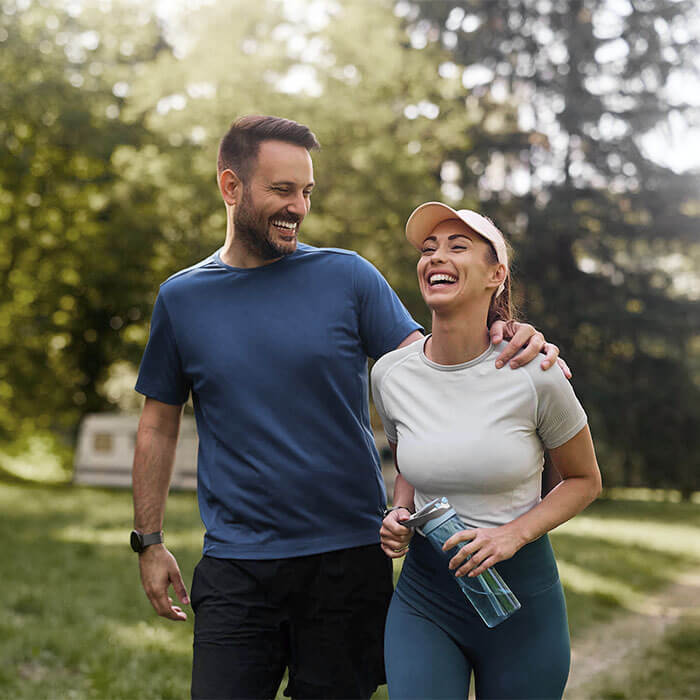 man and woman smiling outdoors on a trail