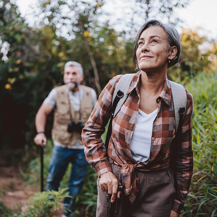 mature woman hiking outdoors with mature man behind her