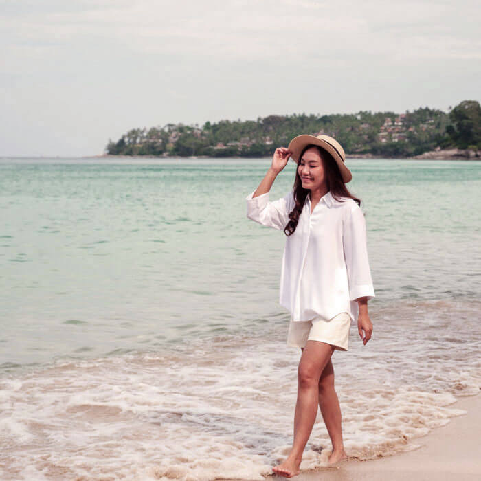 woman wearing sunhat and walking on the beach