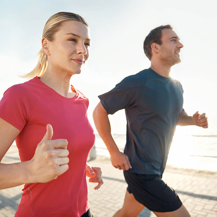 man and woman running together near waterfront
