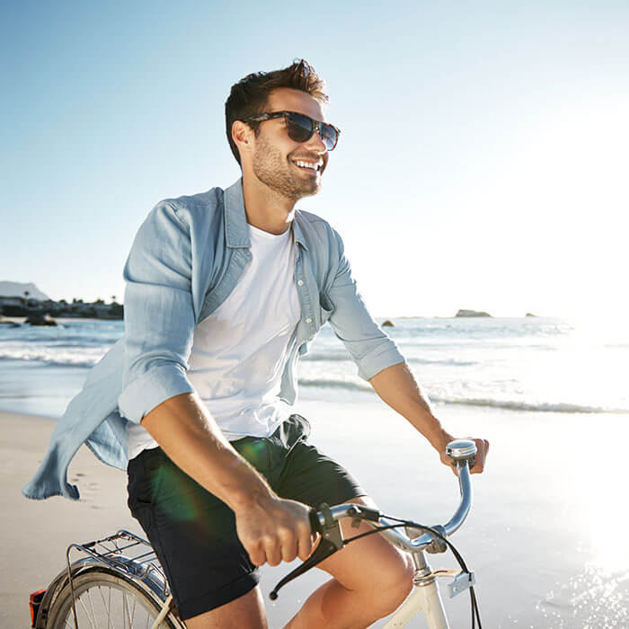 smiling man on bicycle at the beach
