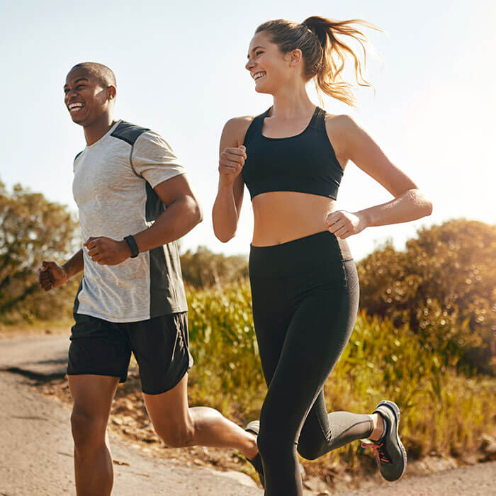 man and woman smiling together on a run outdoors