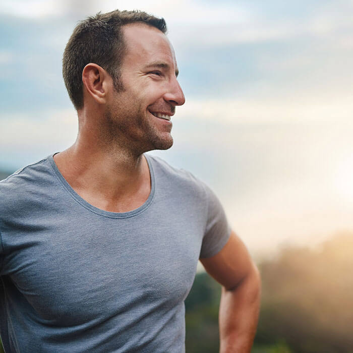 man smiling outdoors and looking to the side
