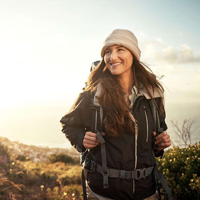 smiling woman hiking on sunny mountain
