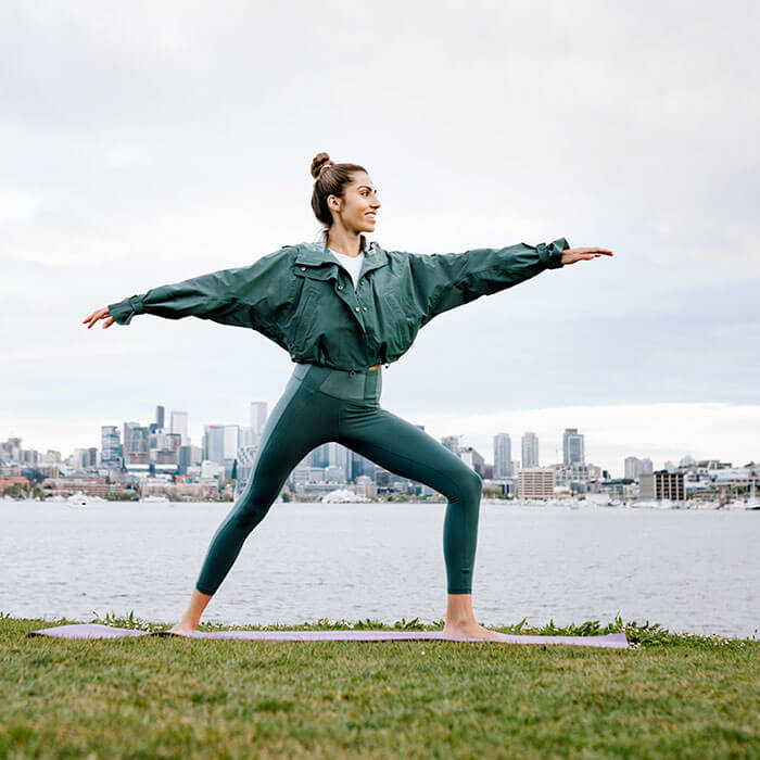 woman doing yoga pose by city waterfront