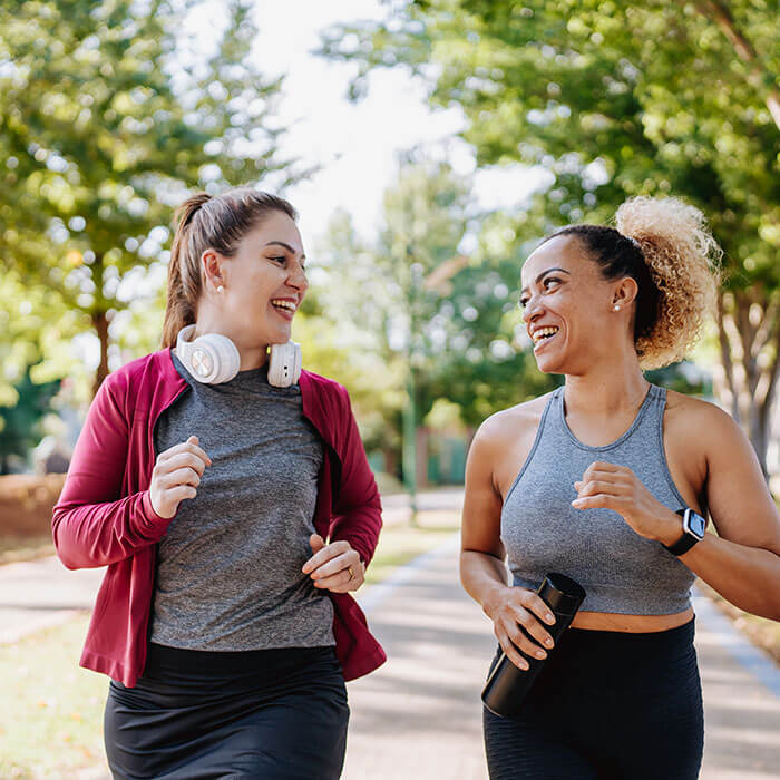 two women laughing together while walking in park