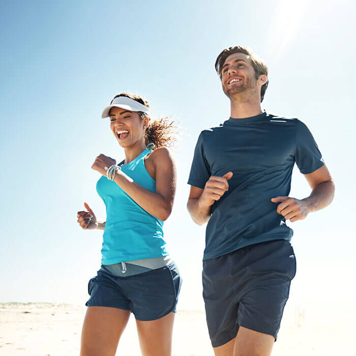 man and woman smiling and jogging together on beach