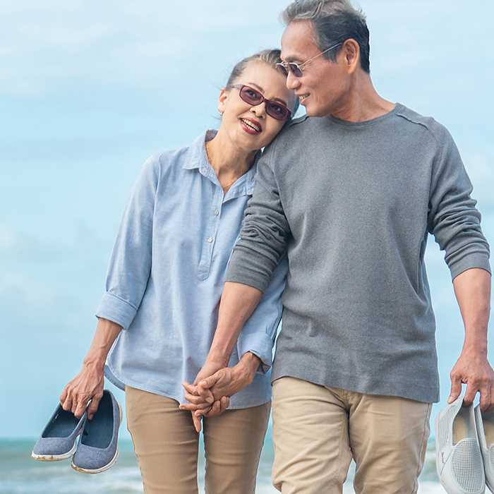 Happy senior asian couple walking on beach