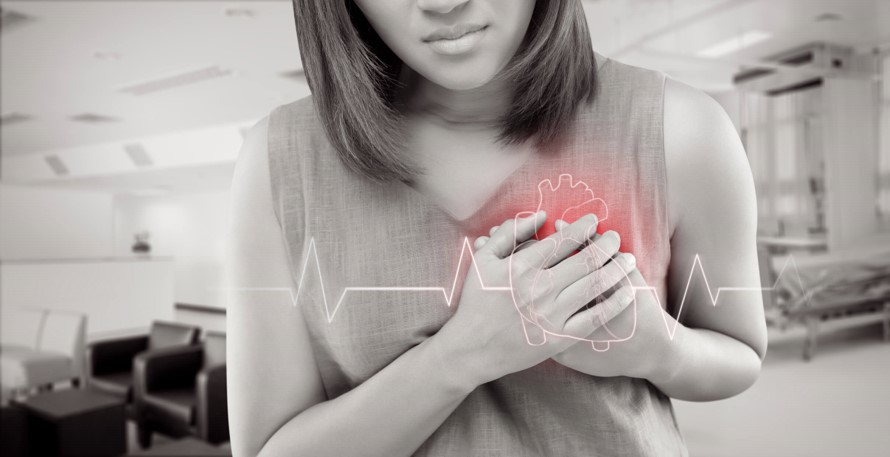 Woman clutching chest with heart pain in hospital setting
