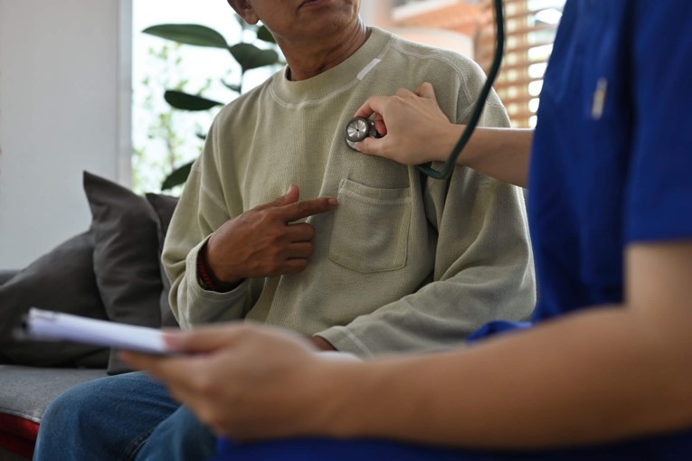 Nurse using stethoscope to listen to patient’s chest during heart checkup